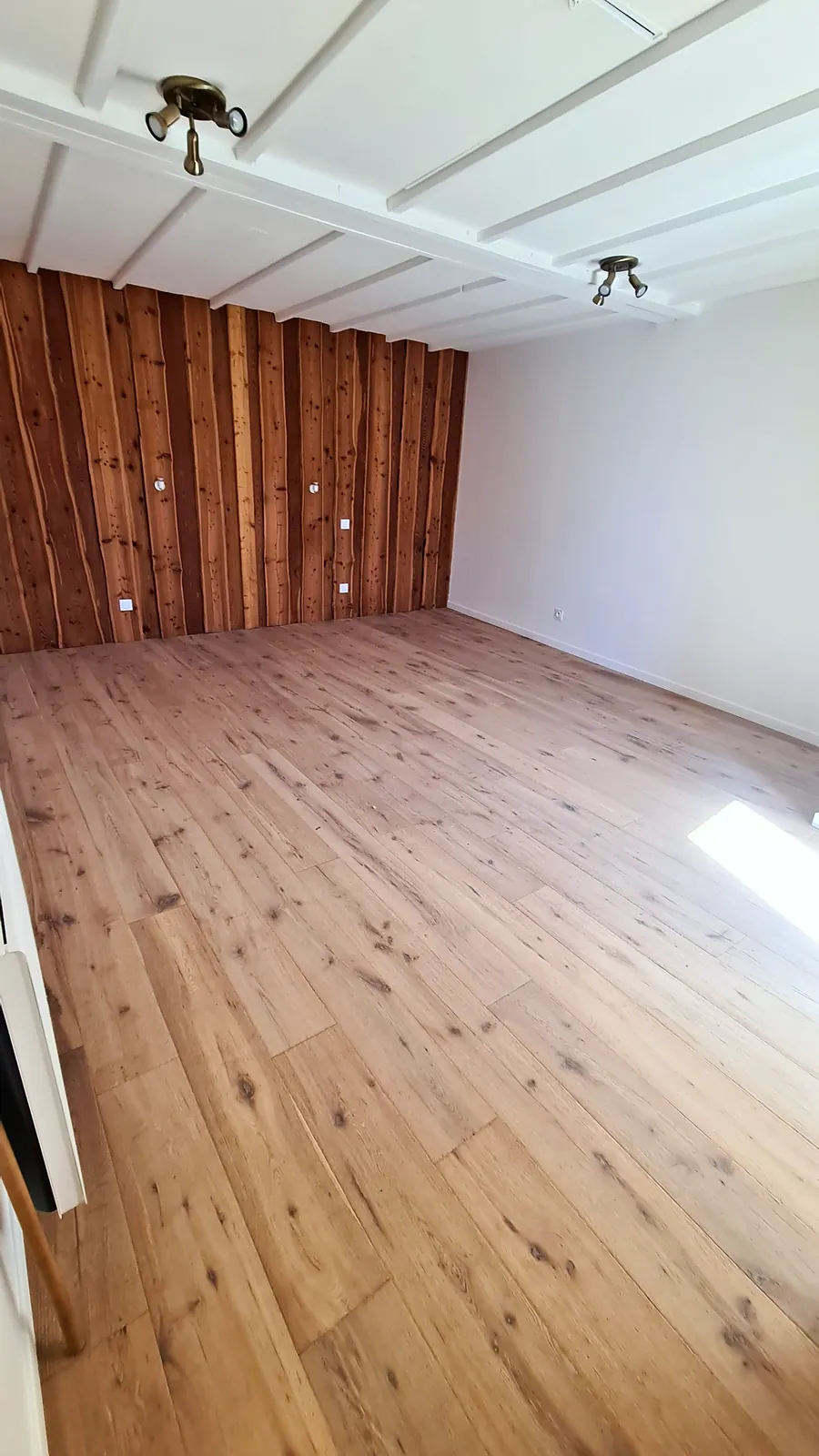 Chambre à l'étage avec parquet et mur en bardage bois
