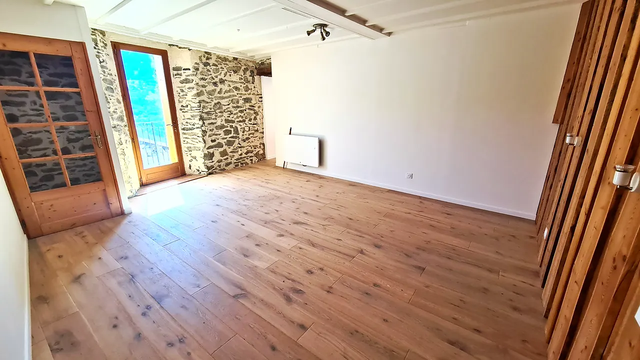 Chambre à l'étage avec porte-fenêtre sur le balcon et mur en pierre