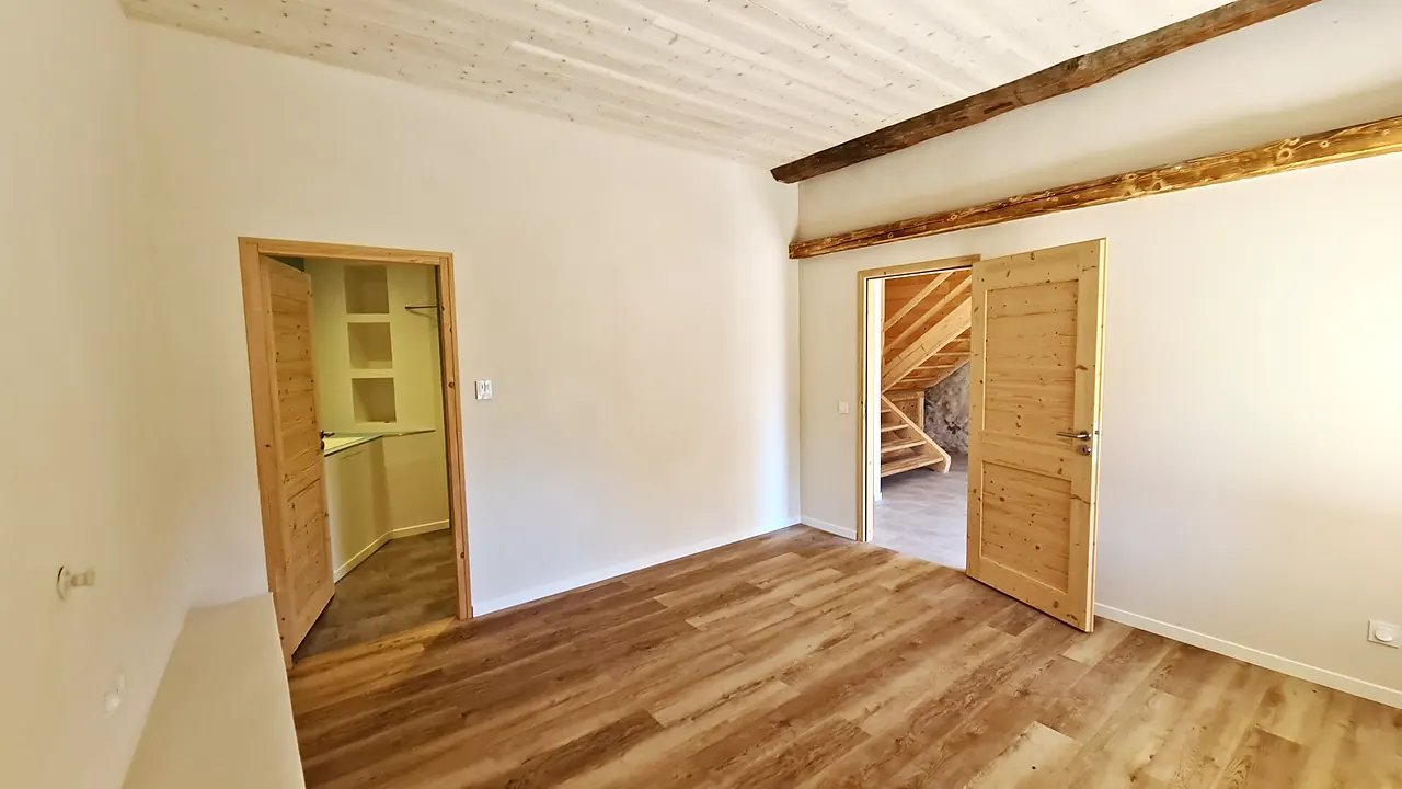 Chambre du rez-de-chaussée avec poutre apparente et portes en bois