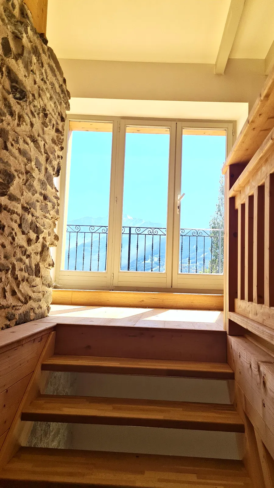 Escalier menant à une baie vitrée ouverte sur la montagne