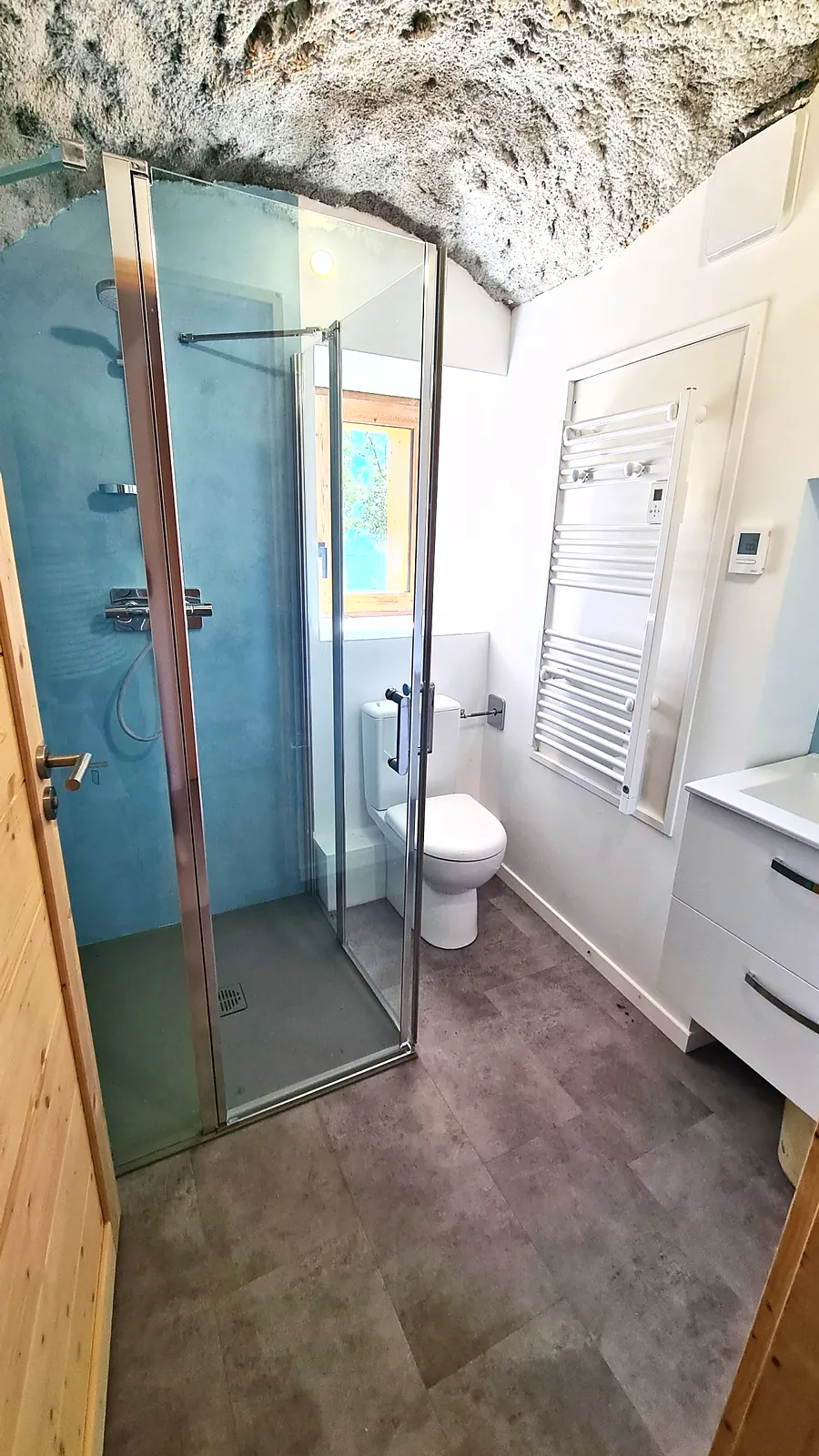 Salle d'eau sous voûte en pierre avec douche vitrée et sèche-serviettes